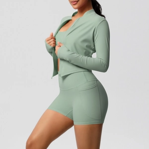 Détail d'un ensemble de yoga vert sauge avec poches sur le short et veste zippée