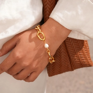 Detail of 18k gold plated chunky chain bracelet with a single white pearl on a wrist