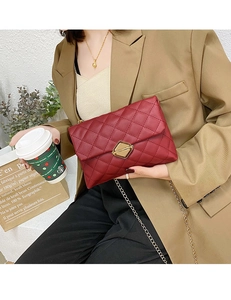 Detail of burgundy quilted PU leather crossbody bag with golden chain and metal lock