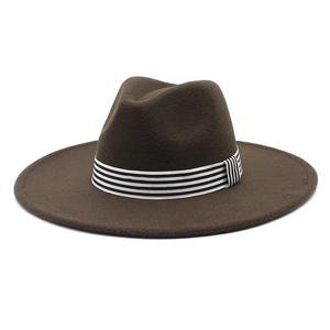 Detail of a dark brown wide brim wool fedora with a black and white striped ribbon band
