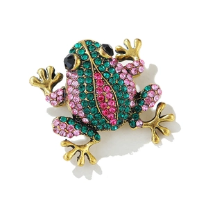 Détail d'une broche grenouille dorée avec strass verts et roses et yeux en gemmes noires