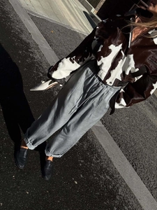Close-up of a stylish faux fur crop jacket with a brown and white cow pattern print