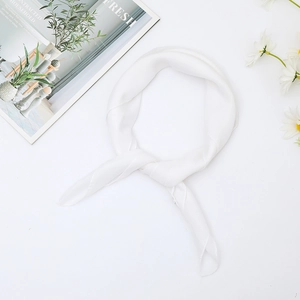 Detail of soft white chiffon square scarf tied in a knot with minimalist home magazine