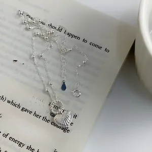 Close-up of silver heart necklace with ribbed texture on an open vintage book