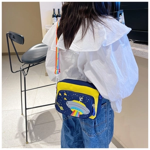 Child wearing a navy and yellow canvas crossbody bag with cartoon UFO and rainbow strap