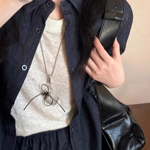 Silver bead chain long necklace with black bow and sparkling square pendant on denim shirt
