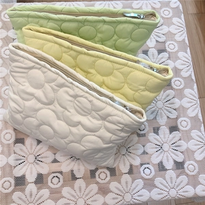 Detailed view of flower-quilted down makeup bags in green, yellow, and white colors