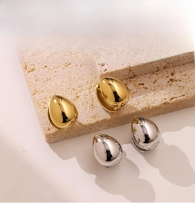 Macro view of teardrop stud earrings in gold and silver with a polished mirror finish