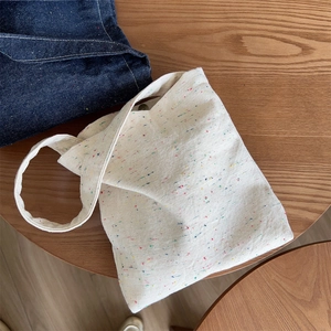 Detail of off-white canvas tote bag with multi-color polka dots on a wooden table