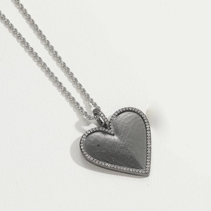 Macro detail of heart pendant with fingerprint texture and crystal pave on twist chain