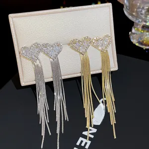 Close-up of elegant gold and silver long tassel earrings with sparkling heart-shaped studs