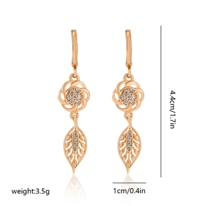 Detail view of gold flower and leaf earrings with white zircon accents and dimensions