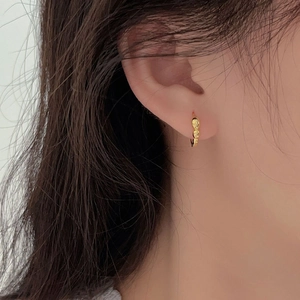 Close-up of minimalist gold 925 sterling silver hoop earring on ear with textured surface