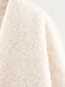 Detailed macro view of soft cream faux shearling fabric on an oversized autumn cardigan