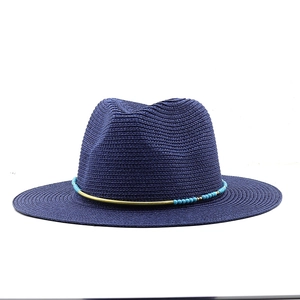 Detailed view of dark blue straw fedora with turquoise beads and golden metal trim decor