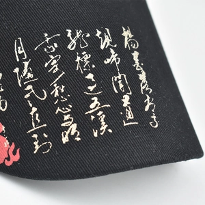 Close-up of black cotton twill baseball cap with golden Chinese calligraphy and red totem