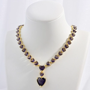 Detail showing a purple heart-shaped zircon pendant on a gold plated necklace