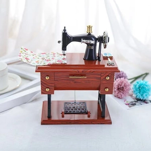 Vintage sewing machine music box with wood grain base and miniature fabric accessories