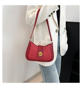 Detail of red glitter underarm bag featuring a gold twist lock on a white suit model