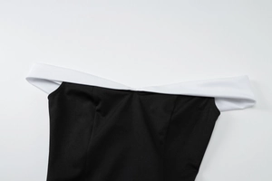 Détail de la robe moulante noire avec encolure bandeau contrastée blanche et finitions
