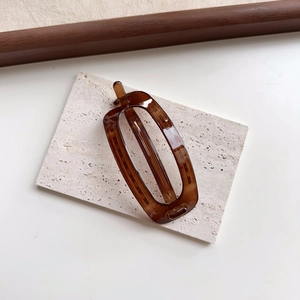 Detail of an amber-colored oval hair clip on a stone tray with natural textures