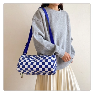 Detail of blue and white checkerboard barrel bag with wide shoulder strap