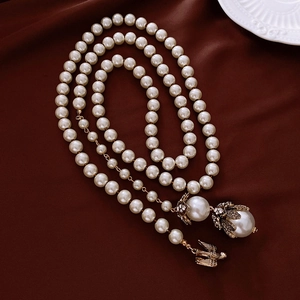 Dettaglio collana di perle vintage con fiore di diamanti e uccello d'oro su seta