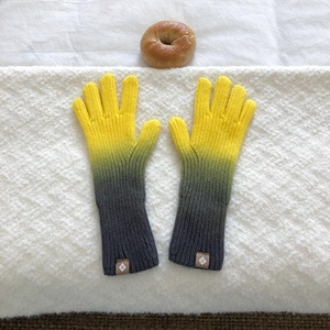 Close-up of yellow and grey gradient knitted gloves with a compass logo tag