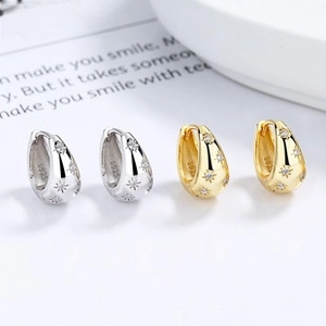 Detail of S925 sterling silver S-shape earrings with zircon star engraving in gold and silver
