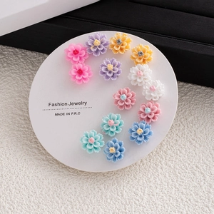Close-up of colorful resin flower stud earrings set on a white display card