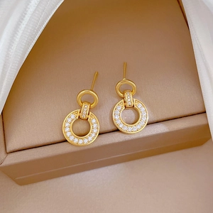Detailed close-up of gold interlocking double hoop earrings with paved white zircons