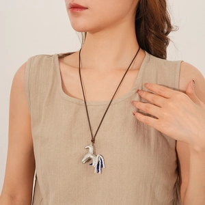 Detail of silver horse pendant with blue and white bead fringe on long wax cord