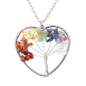 Macro shot of silver-tone tree of life heart pendant with multicolor gemstone chips