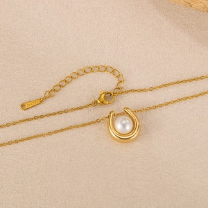 Detail of gold U-shaped pendant with white pearl and S-STEEL tag on fine chain