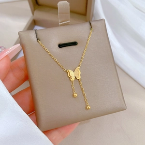 Detailed close-up of a gold butterfly pendant necklace with small bead tassels