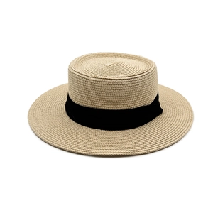 Close-up of woven straw texture and wide black ribbon on a khaki flat top sun hat