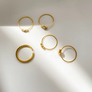 Set of five gold stacking rings with cubic zirconia leaves and rhinestones on white background