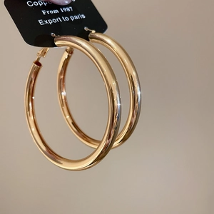 Close-up of polished golden hoop earrings featuring a minimalist large circular design