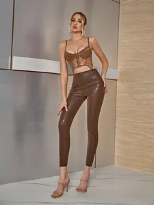 Dettaglio top a corsetto in pizzo marrone e pantaloni in ecopelle pitonata in interni moderni