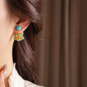 Gros plan de boucles d'oreilles fleurs en filigrane doré avec perles turquoise