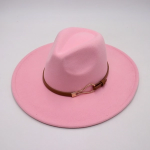 Detail of pink wool fedora hat featuring a brown leather strap and gold metal buckle
