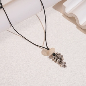 Detail of wax rope necklace with resin ring and silver metallic grape pendant cluster