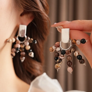 Detail of silver tassel earrings with brown natural stone beads on a female model