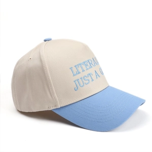 Detail of blue embroidery text on a two-tone beige and blue cotton baseball cap