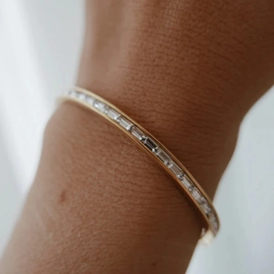 Pulsera de acero inoxidable dorada con circonitas rectangulares en muñeca femenina