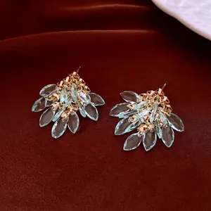Elegant gold fringe earrings with light blue marquise crystals on red velvet background