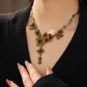 Détail d'un collier vintage en forme de fleur avec strass orange et violet sur un mannequin