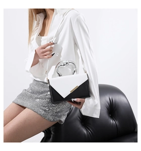 Detail of color-block crossbody bag featuring sleek metal handle and premium leather texture