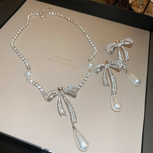 Detail of zircon bowknot necklace and water drop pearl earrings set on a display board