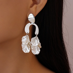 Detailed close-up of a silver U-shaped earring with white acrylic flower petals on a model